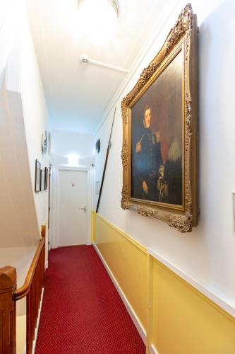 a hallway with a painting on the wall and a red carpet at Amsterdam Wiechmann Hotel in Amsterdam