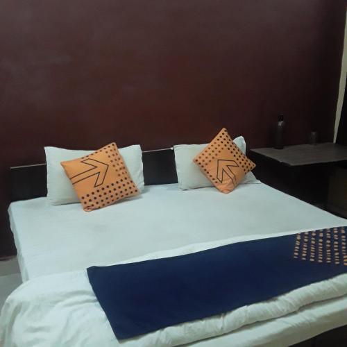 a bed with orange and blue pillows on it at shri bake bihari guest house in Gwalior