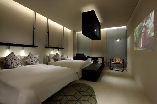 a hotel room with two beds and a desk at The Place Tainan in Tainan
