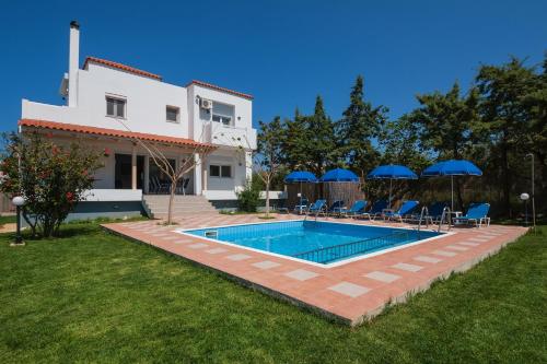 a villa with a swimming pool in front of a house at Romantic Evas Cottage in Gouves