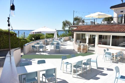 een patio met witte tafels en stoelen en de oceaan bij Campeggio della Colombaia in Padenghe sul Garda