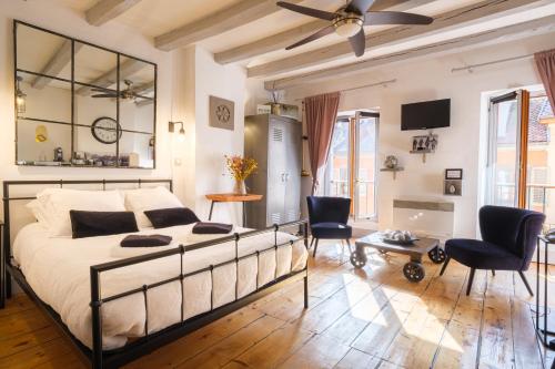 une chambre avec un lit, des chaises et une télévision dans l'établissement Au Grey d’Annecy, studio cosy au cœur de la ville, à Annecy