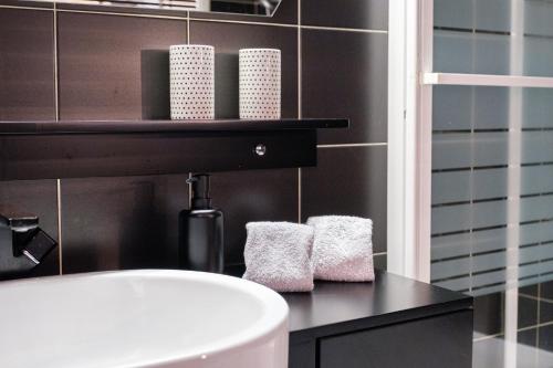 La salle de bains est pourvue d'un lavabo blanc et de serviettes sur un comptoir. dans l'établissement Au Grey d’Annecy, studio cosy au cœur de la ville, à Annecy