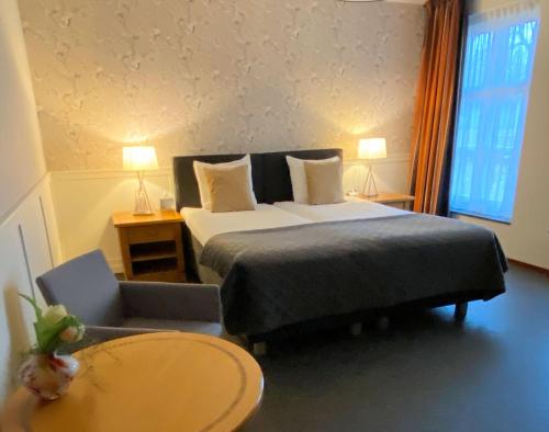 a bedroom with a bed and a table and a chair at Hotel Hof van 's Gravenmoer in 's-Gravenmoer