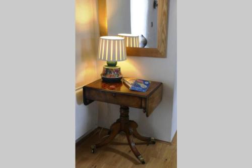 a lamp on a table in a corner with a mirror at Rural 17th century barn studio apartment in Cheriton Bishop