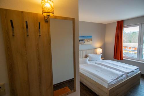 a mirror in a bedroom with a bed and a window at Hotel Wikinger in Zempin
