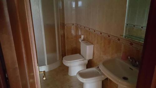 ein Badezimmer mit weißer Toilette und Waschbecken in der Unterkunft Piso cerca de la playa in Boiro