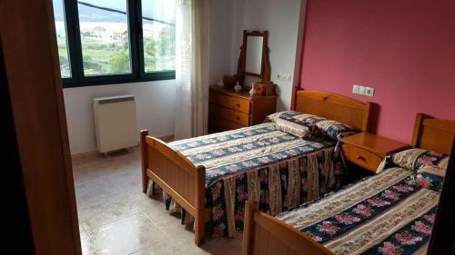 a bedroom with two beds and a dresser and a window at Piso cerca de la playa in Cerceda