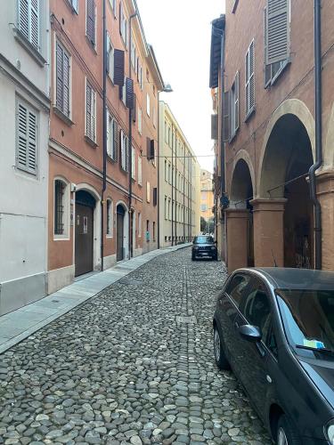 a car parked on a cobblestone street next to buildings at Empire - Affittacamere in Modena