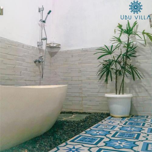 uma casa de banho com uma banheira e um vaso de plantas em Ubu Villa Gito Gati - 4 Bedrooms Villa near Yogyakarta City Center em Ngaglik