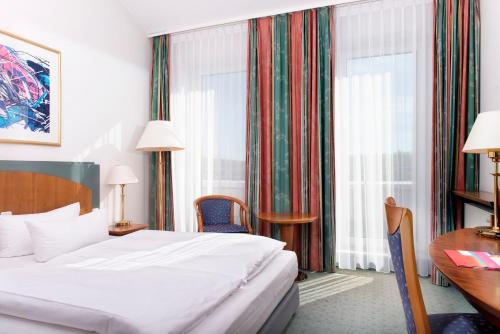 una camera d'albergo con letto, scrivania e finestra di Congress Hotel Weimar by Mercure a Weimar