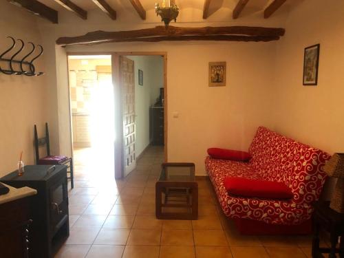 a living room with a red couch and a table at CASA RURAL LLAVADOR Vall Guadalest in Benifató