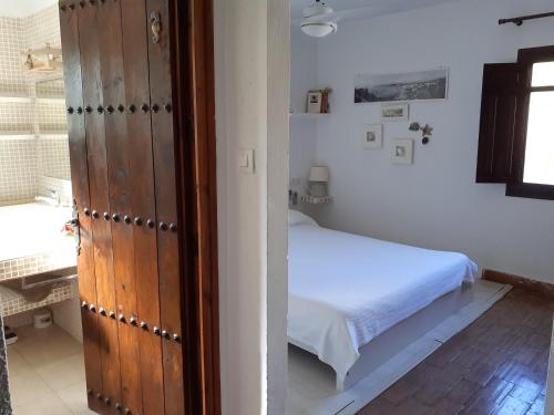 a small bedroom with a bed and a door at CASA PIZZI in Agua Amarga