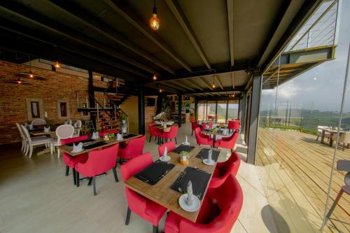 a restaurant with red chairs and tables and windows at The Plains Green in Ambawela
