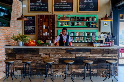 a man standing behind a bar with stools at The Plains Green in Ambawela