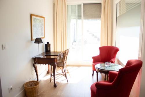 a living room with a table and a red chair at Hotel Hacienda Montenmedio in Vejer de la Frontera