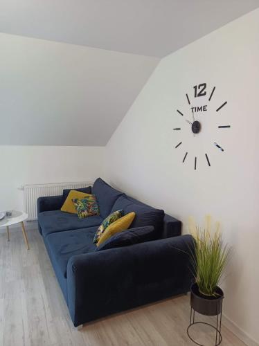 a blue couch in a living room with a clock on the wall at Apartament Kruklanki in Kruklanki