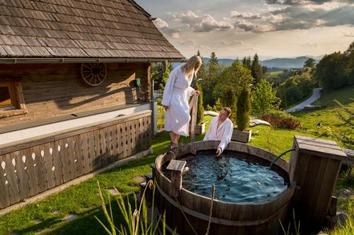 a woman standing next to a hot tub with a man in it at Landhotel Spreitzhofer in Sankt Kathrein am Offenegg