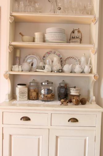 a white cabinet filled with dishes and plates at B&B La Foglia Verde in Massa