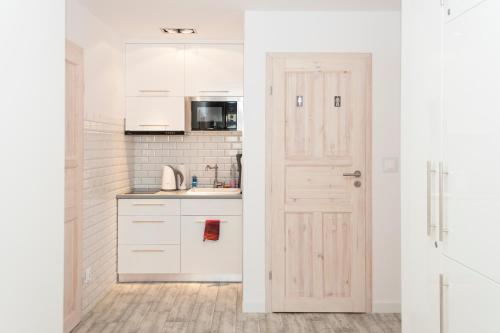a kitchen with white cabinets and a door at HeroHostel in Sieradz