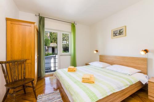 een slaapkamer met een bed, een stoel en een raam bij DADA in Novi Vinodolski