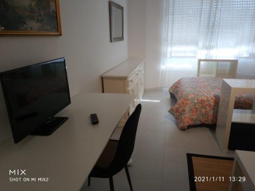 Habitación con escritorio, TV y cama. en Resitur Apto 731, en Sevilla