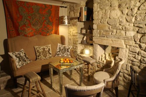 a living room with a couch and a stone wall at La Maison du Passage - Chambres - Suites premium, Spa, Piscine et Restaurant in Martignargues