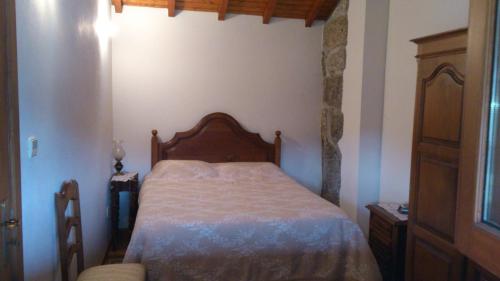 a bedroom with a bed with a wooden head board at Casa do Faroca in Vieira do Minho