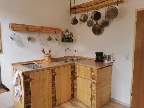una cocina con armarios de madera, fregadero, ollas y sartenes en Der Blankhof "Back to Roots", en Bad Endorf