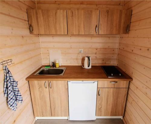 a small kitchen with a sink and a refrigerator at Zaciszne Gąski - domki letniskowe in Gąski