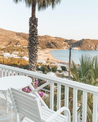 a white balcony with a table and a palm tree at Far Out Hotel & Spa in Mylopotas