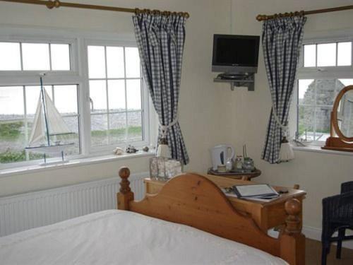 um quarto com uma cama, uma televisão e janelas em 1-Bed Cottage on Coastal Pathway in South Wales em Gileston