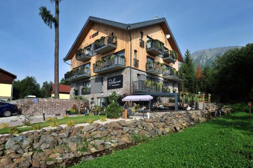 a building with a stone wall in front of it at APLEND Vila Olívia in Smokovce