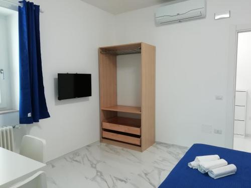 1 dormitorio con 1 cama y TV en la pared en L'Altare Bianco, en Vieste