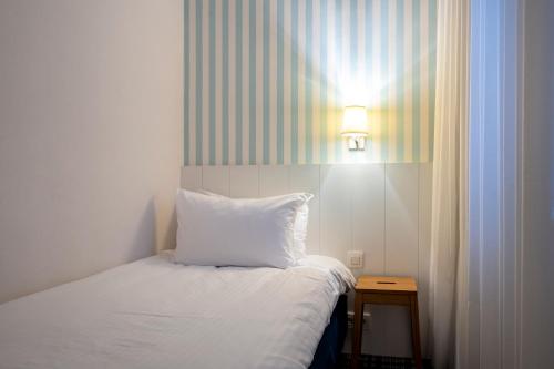 a bedroom with a bed with a white pillow and a light at Leopold Hotel Ostend in Ostend