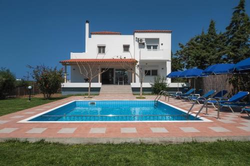 a villa with a swimming pool in front of a house at Romantic Evas Cottage in Gouves