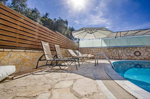 a pool with chairs and an umbrella next to a fence at Lea Family Resort in Kassiopi