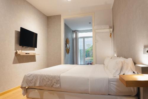 1 dormitorio con 1 cama blanca y TV en Cosmopolitan Boutique Rambla, en Barcelona