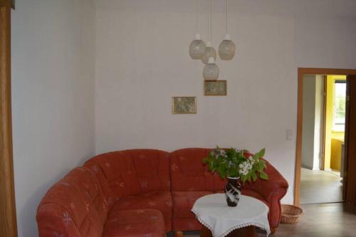 a living room with a red couch and a table with flowers at Ferienhaus Hüthchen in Eichhorst