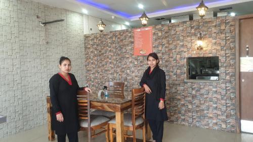 two women in black robes standing next to a table at Maple Leaf Hotel in Kharar