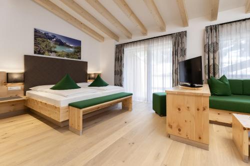 a bedroom with a bed and a couch and a tv at Hotel Tauernhof in Kaprun