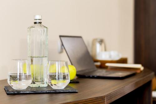 a bottle and two glasses on a table with a laptop at Prestige Boutique Hotel Craiova in Craiova