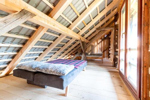 Cama en habitación con techos y ventanas de madera en Glamping - Hayrack Vesel en Trebnje