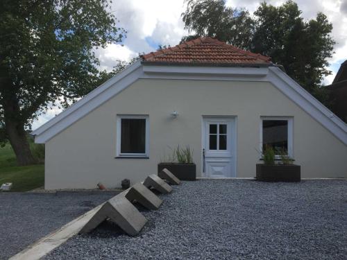 een klein wit gebouw met een deur ervoor bij Ferienhaus Kaept n Poldi 25192 in Bunde