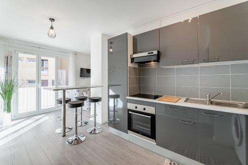 une cuisine équipée d'appareils en acier inoxydable et d'un comptoir avec tabourets dans l'établissement Le Levantés par Dodo-a-Cassis, à Cassis