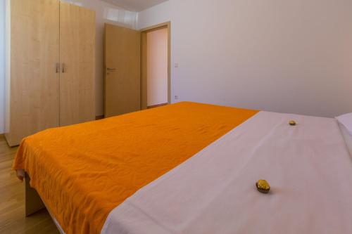 a bedroom with a bed with an orange and white blanket at DAKOVIC TIHANA in Šilo