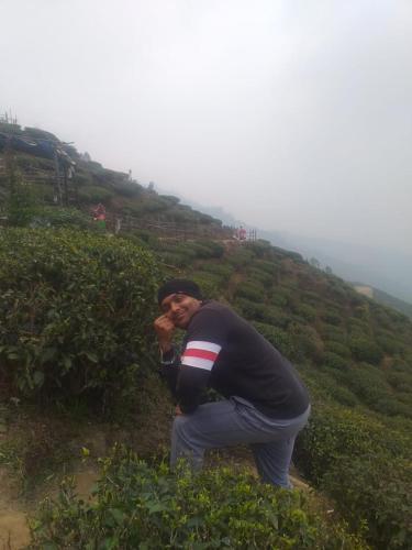 a man standing on a hill with his hand to his face at Madys view -Aaple Ghar in Darjeeling
