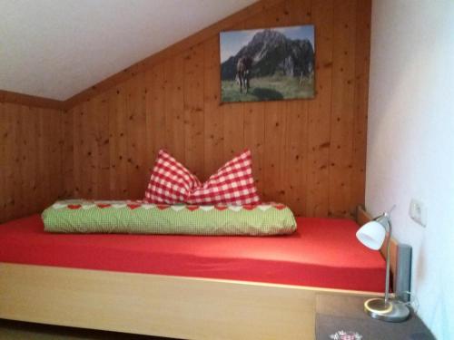 łóżko z białymi i czerwonymi poduszkami w pokoju w obiekcie Ferienwohnung Dopfer w mieście Eisenberg