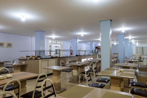 a restaurant with tables and chairs and a kitchen at Hotel Baviera Iguassu in Foz do Iguaçu