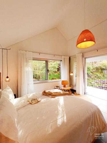a bedroom with a large white bed and two windows at Casas do Morgadio in Biscoitos